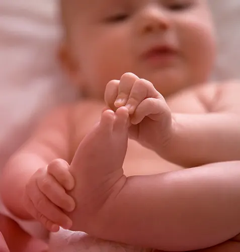 Bebê deitado segurando o próprio pé